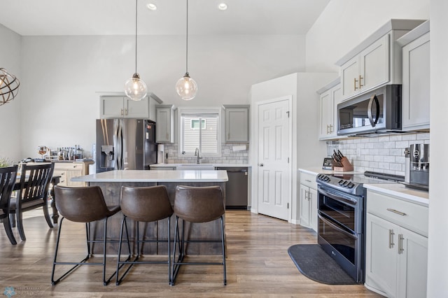 977 Ashley Dr W, West Fargo, ND 58078 - kitchen with stainless steel appliances, a center island, decorative backsplash, a breakfast bar, and light countertops