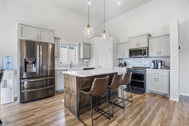 977 Ashley Dr W, West Fargo, ND 58078 - kitchen featuring stainless steel appliances, light countertops, a kitchen island, decorative backsplash, and high vaulted ceiling
