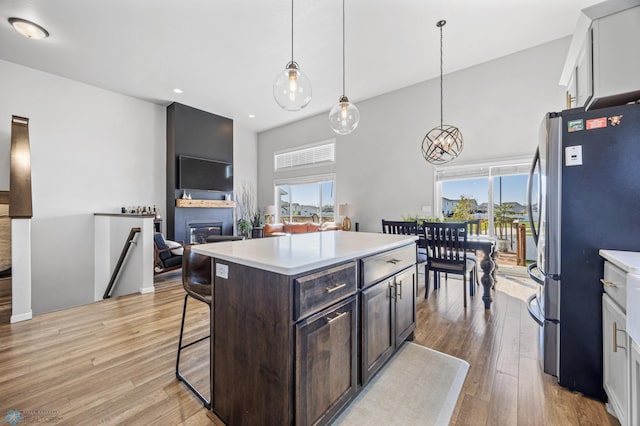 977 Ashley Dr W, West Fargo, ND 58078 - kitchen with freestanding refrigerator, a towering ceiling, light countertops, a breakfast bar, and a glass covered fireplace
