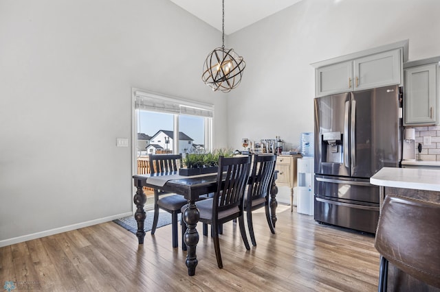 977 Ashley Dr W, West Fargo, ND 58078 - dining area featuring a chandelier, light wood-style floors, a towering ceiling, and baseboards