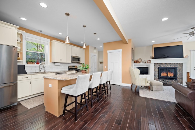 1013 Planters Path, Bayport, MN 55003 - kitchen with appliances with stainless steel finishes, open floor plan, ceiling fan, a kitchen island, and light stone counters