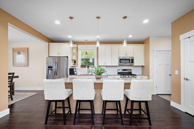 1013 Planters Path, Bayport, MN 55003 - kitchen with appliances with stainless steel finishes, an island with sink, backsplash, baseboards, and a kitchen breakfast bar