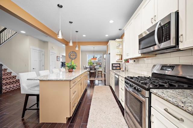 1013 Planters Path, Bayport, MN 55003 - kitchen featuring stainless steel appliances, a center island, a breakfast bar area, dark wood-style floors, and backsplash