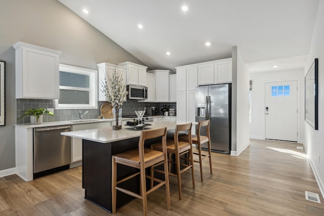 1951 Fulton Rd, Carver, MN 55315 - kitchen featuring appliances with stainless steel finishes, a breakfast bar area, a center island, white cabinets, and lofted ceiling