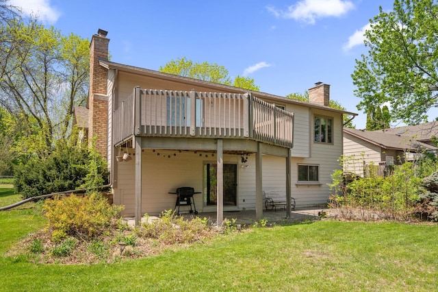 rear view of house featuring a chimney, a yard, a patio area, and a balcony