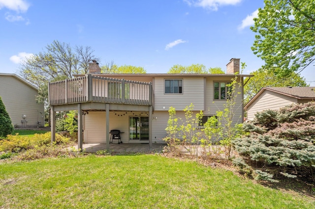 rear view of property with a chimney, a lawn, a patio, and a wooden deck