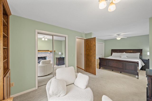carpeted bedroom with two closets, a brick fireplace, and baseboards