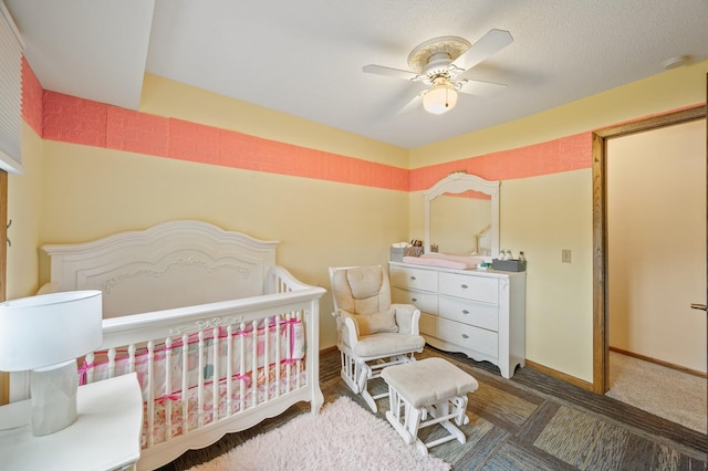 bedroom featuring baseboards, a crib, and ceiling fan