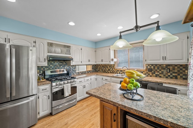 kitchen with stainless steel appliances, white cabinets, decorative backsplash, beverage cooler, and light wood-style floors