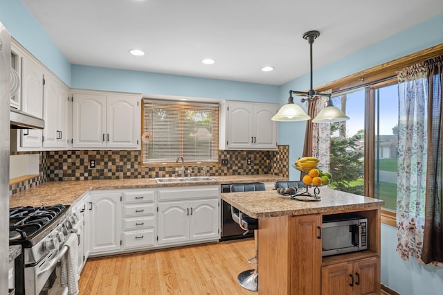 kitchen featuring appliances with stainless steel finishes, a sink, light countertops, white cabinetry, and backsplash