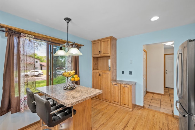 kitchen with freestanding refrigerator, light countertops, a center island, and decorative light fixtures