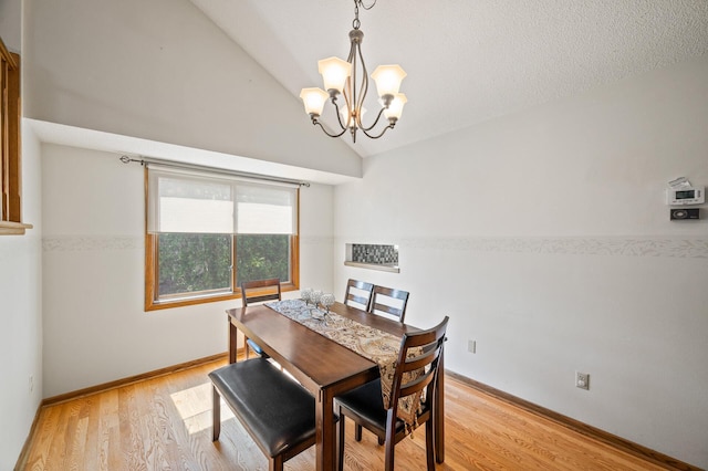 dining room featuring a chandelier, light wood-style floors, lofted ceiling, and baseboards