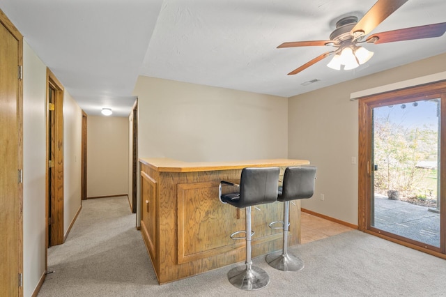 bar featuring light colored carpet, baseboards, and a ceiling fan