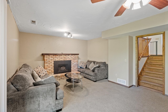living room featuring carpet flooring, stairway, a fireplace, a ceiling fan, and baseboards