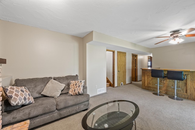 living area featuring a dry bar, light carpet, stairs, and a ceiling fan