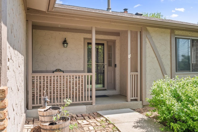 property entrance featuring covered porch and stucco siding