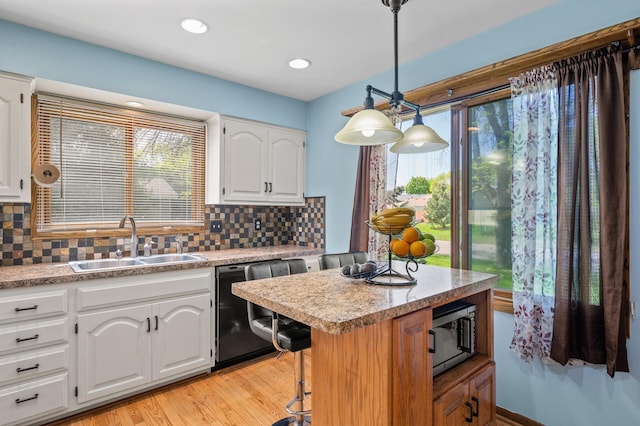 kitchen featuring dishwasher, stainless steel microwave, a sink, backsplash, and light countertops