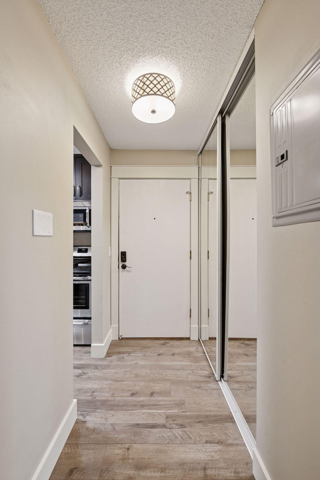 215 Barry Ave S Unit 306, Wayzata, MN 55391 - hallway featuring a textured ceiling, light wood-style flooring, and baseboards