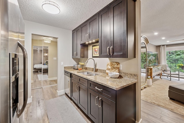 215 Barry Ave S Unit 306, Wayzata, MN 55391 - kitchen with stainless steel appliances, a sink, a textured ceiling, dark brown cabinets, and light wood-style floors