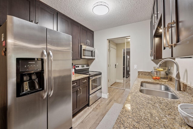215 Barry Ave S Unit 306, Wayzata, MN 55391 - kitchen featuring stainless steel appliances, a sink, dark brown cabinetry, light wood-type flooring, and light stone countertops