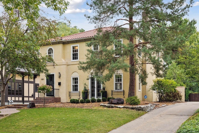 mediterranean / spanish-style home featuring stucco siding, a front lawn, and a tile roof