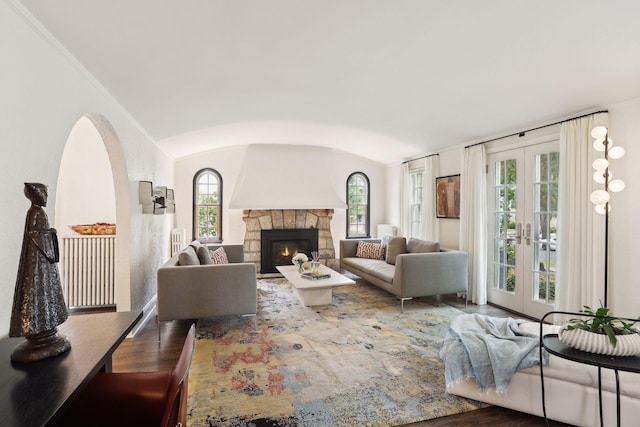 living room featuring wood finished floors, french doors, vaulted ceiling, and a fireplace