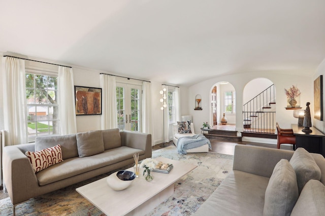 living area featuring healthy amount of natural light, french doors, wood finished floors, stairway, and lofted ceiling