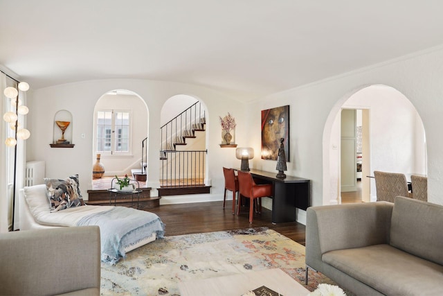 living area featuring arched walkways, wood finished floors, stairway, and baseboards
