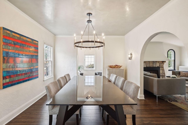 dining room featuring crown molding, a chandelier, baseboards, wood finished floors, and arched walkways