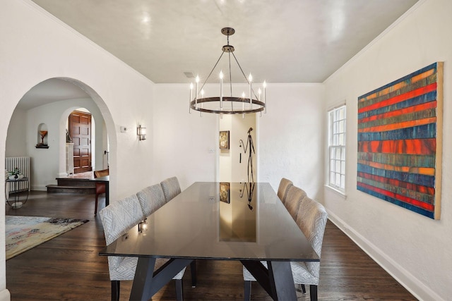 dining room with crown molding, a chandelier, wood finished floors, baseboards, and arched walkways