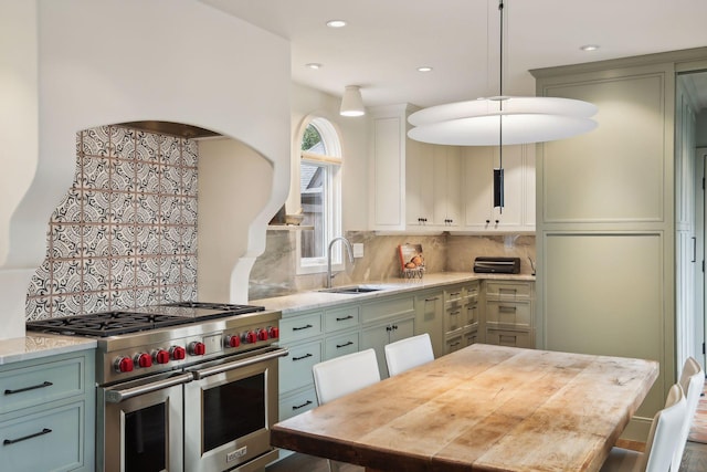 kitchen featuring range with two ovens, a sink, decorative backsplash, decorative light fixtures, and recessed lighting
