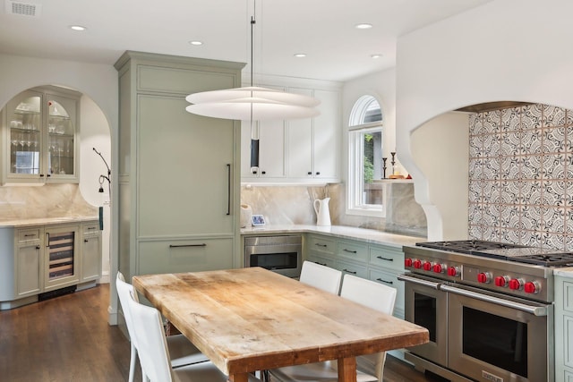 kitchen featuring double oven range, tasteful backsplash, green cabinets, dark wood-style flooring, and beverage cooler
