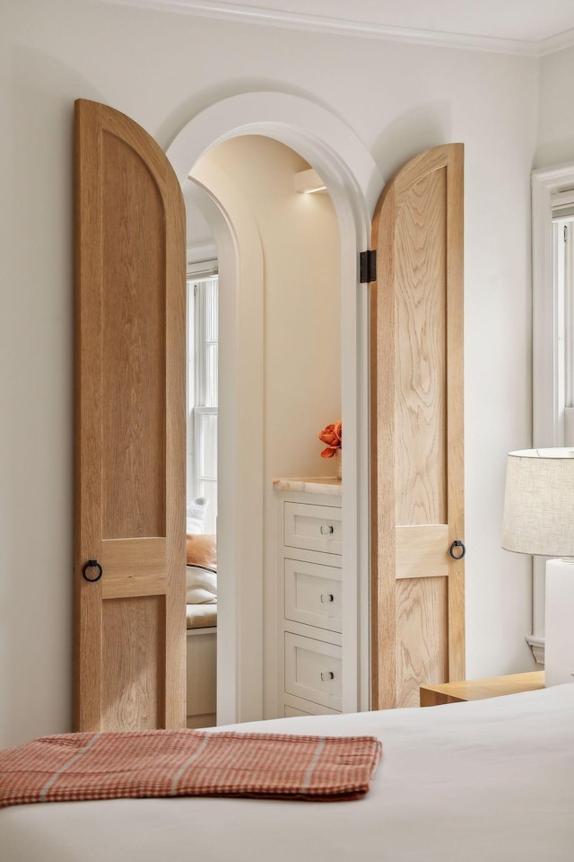 bedroom featuring arched walkways and crown molding