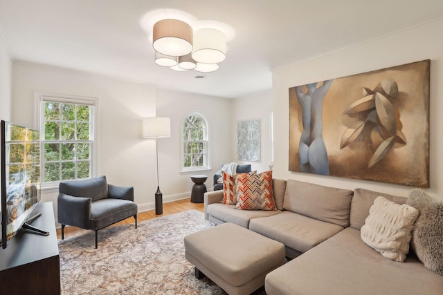 living area featuring wood finished floors, healthy amount of natural light, a chandelier, baseboards, and crown molding