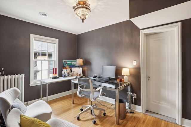 office space featuring radiator heating unit, wood finished floors, baseboards, and a chandelier