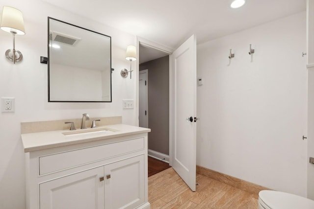 bathroom featuring wood finished floors, vanity, toilet, recessed lighting, and baseboards