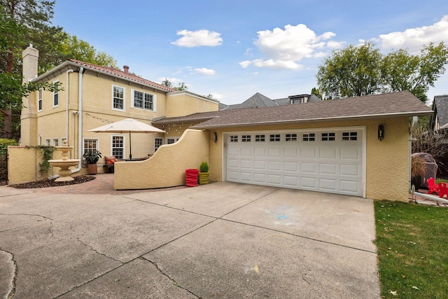 view of front of house featuring concrete driveway, stucco siding, a garage, and a chimney