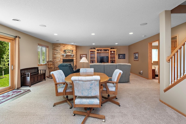 dining room with light colored carpet, a fireplace, a textured ceiling, recessed lighting, and baseboards