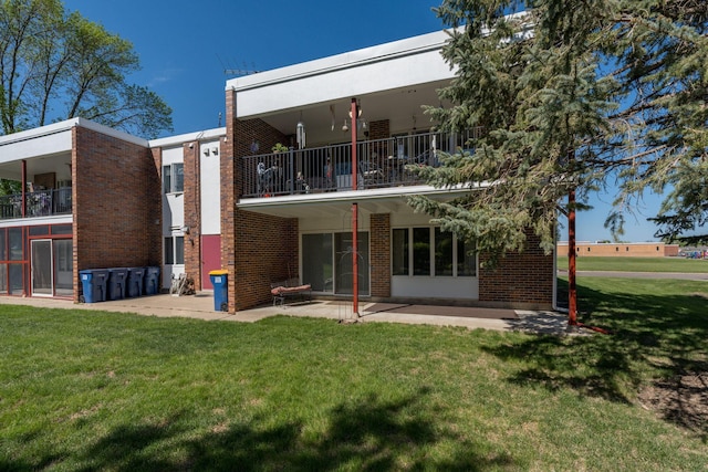 529 Spring St Unit 4, Kenyon, MN 55946 - back of property with a balcony, a patio, a lawn, and brick siding
