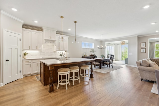 8014 Walnut Ln, Corcoran, MN 55340 - kitchen with open floor plan, an island with sink, white cabinetry, crown molding, and light countertops