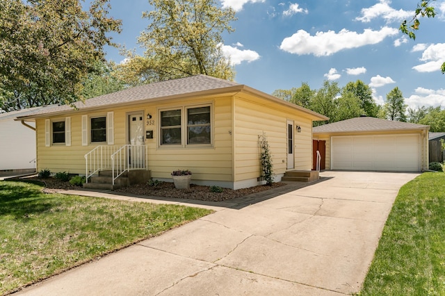 single story home featuring a detached garage, a shingled roof, and a front yard