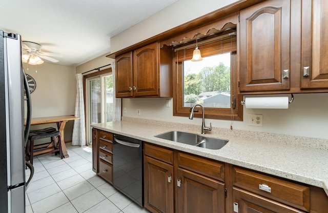 kitchen with freestanding refrigerator, a sink, black dishwasher, a ceiling fan, and light tile patterned flooring