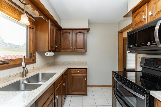 kitchen with range with two ovens, a sink, light tile patterned floors, hanging light fixtures, and baseboards