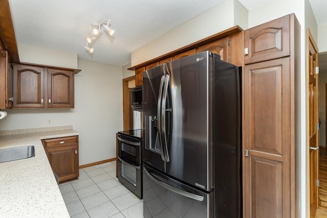 kitchen featuring stainless steel appliances, light countertops, light tile patterned floors, rail lighting, and a sink