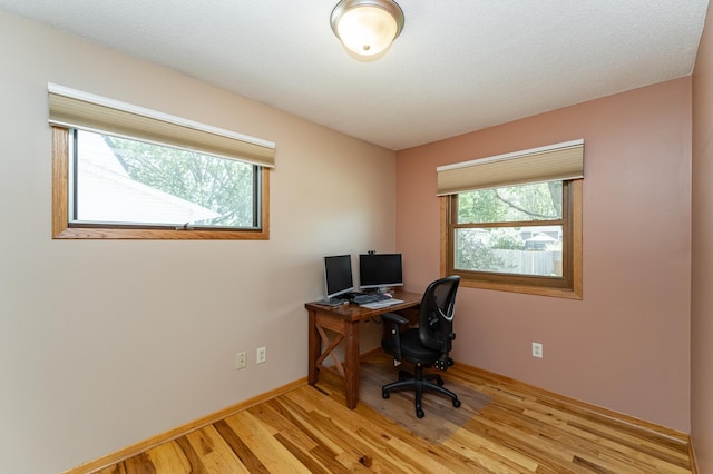 home office with light wood-style flooring and baseboards