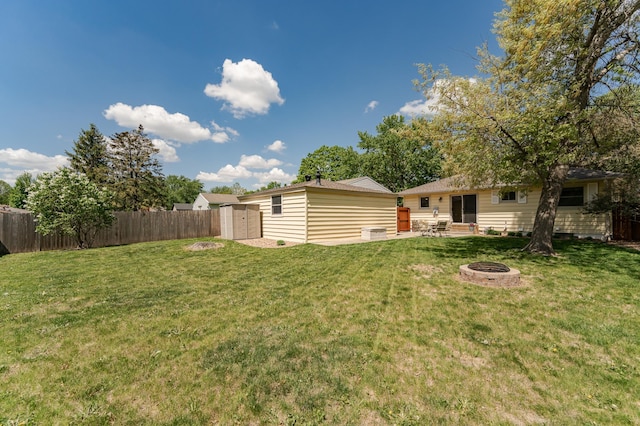 view of yard featuring a fire pit, an outbuilding, and a storage unit