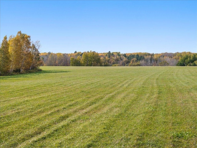 view of green lawn featuring a view of countryside and a view of trees