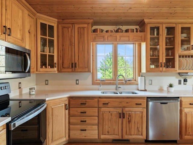 kitchen featuring appliances with stainless steel finishes, a sink, wooden ceiling, light countertops, and glass insert cabinets