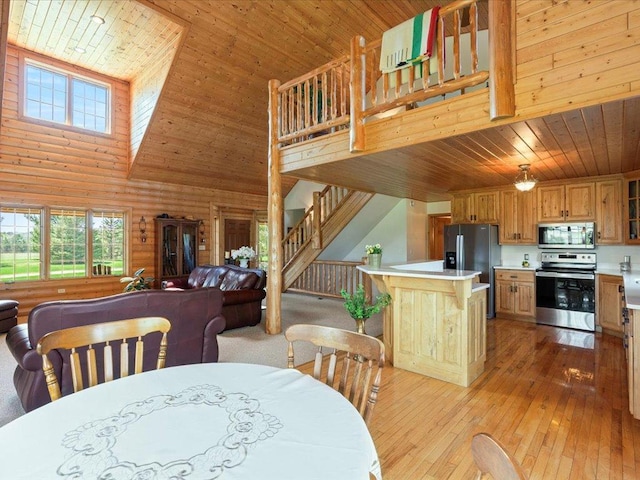 dining space with wooden ceiling, a high ceiling, plenty of natural light, light wood-style floors, and stairs