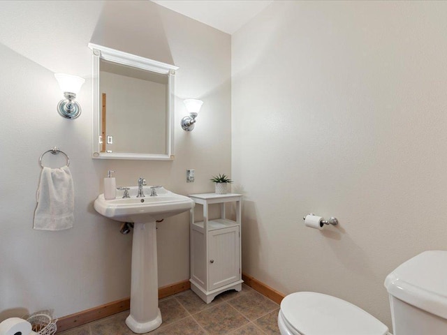 half bath with toilet, baseboards, and tile patterned flooring
